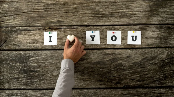 Male hand placing a heart made of marbel in romantic phrase I lo — Stock Photo, Image