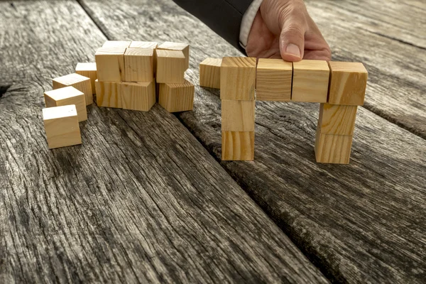 Närbild på affärsman bildar en bro av små träklossar — Stockfoto