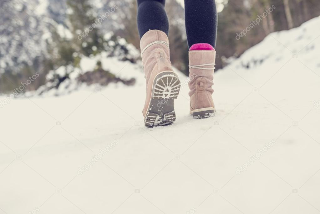 Active woman walking away from the camera through winter snow 