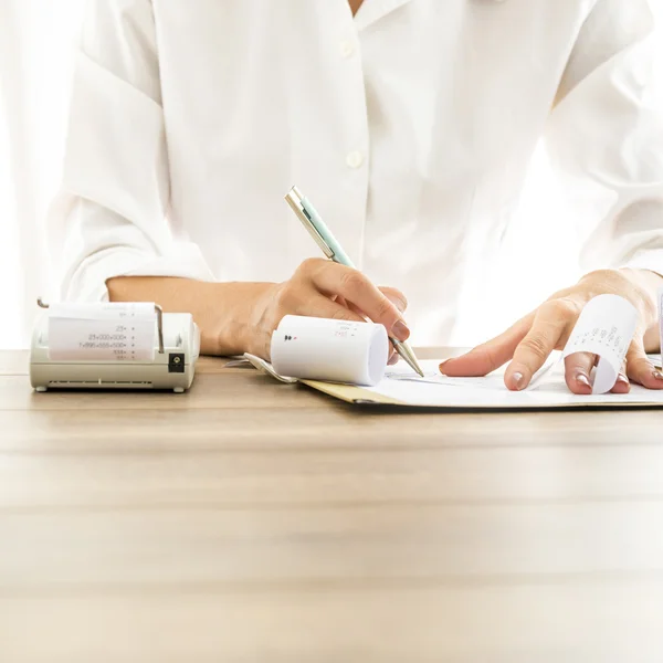 Front view of female bank employee writing something on receipts — Stock Photo, Image