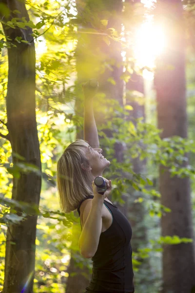 Ευτυχισμένος ξανθιά νεαρή γυναίκα που κάνει pilates άσκηση σε ένα δάσος στο s — Φωτογραφία Αρχείου