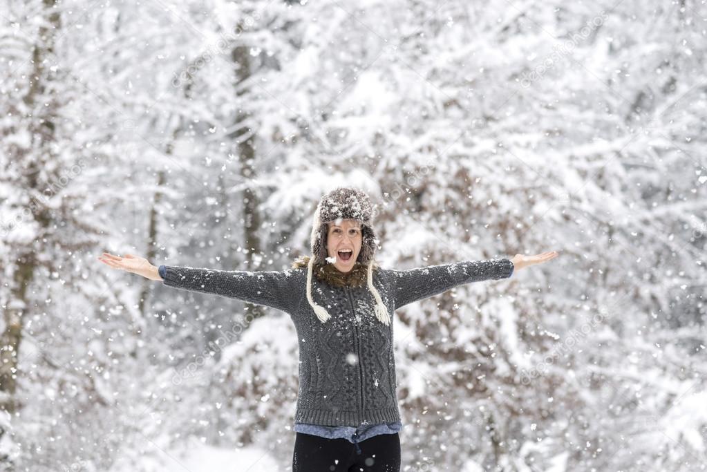 Excited young woman playing in snowy woods