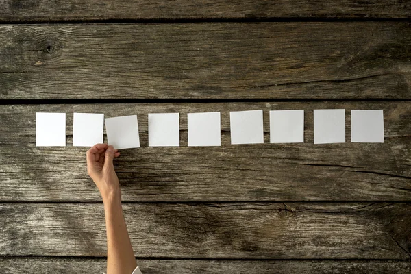 Vista aérea de la mano femenina colocando nueve tarjetas blancas en blanco en un — Foto de Stock