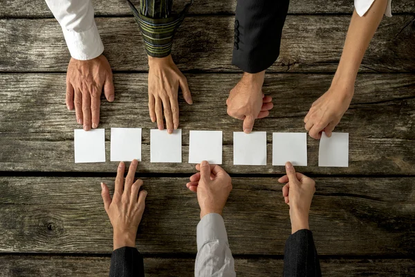 Siete manos de gente de negocios colocando siete tarjetas blancas en una r — Foto de Stock