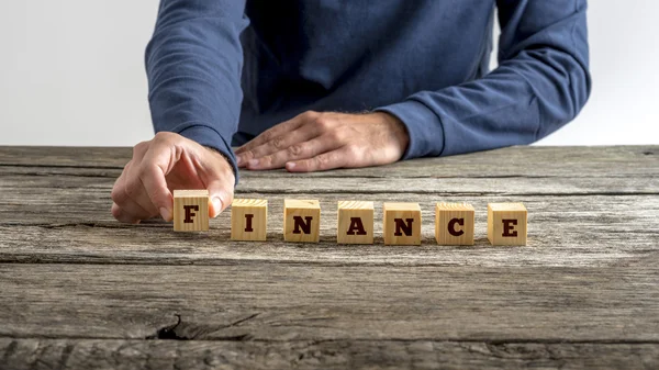 Front view of man in blue shirt assembling the word Finance — Stock Photo, Image