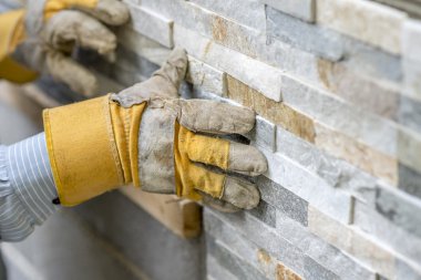 Closeup of manual worker in protection gloves pushing the tile i clipart