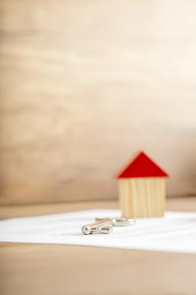 Wooden house miniature and house key lying on contract — Stock Photo, Image