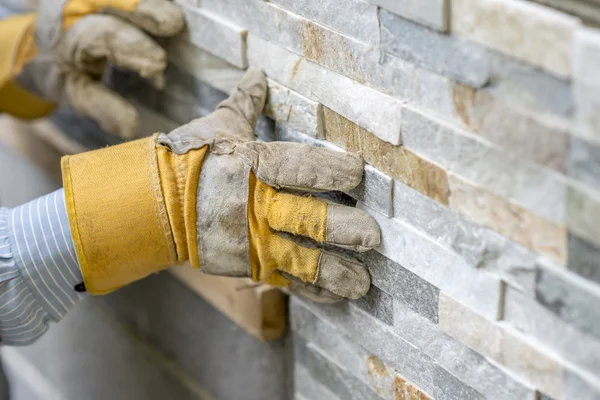 Closeup of manual worker in protection gloves pushing the tile i — Stock Photo, Image