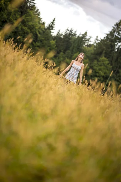 Junge Frau steht auf einer Herbstwiese und blickt in den Himmel — Stockfoto