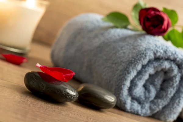 Romantic atmosphere with a red rose on top of rolled towel, lit — Stock Photo, Image