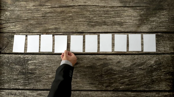 Overhead view of salesman placing 10 blank white cards in a row — Stock Photo, Image