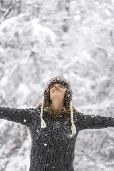 Mujer joven celebrando el invierno con los brazos extendidos —  Fotos de Stock