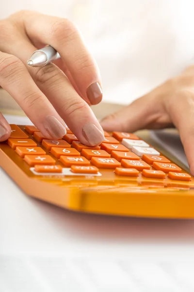 Closeup of female student hand calculating using orange desk cal — Foto de Stock