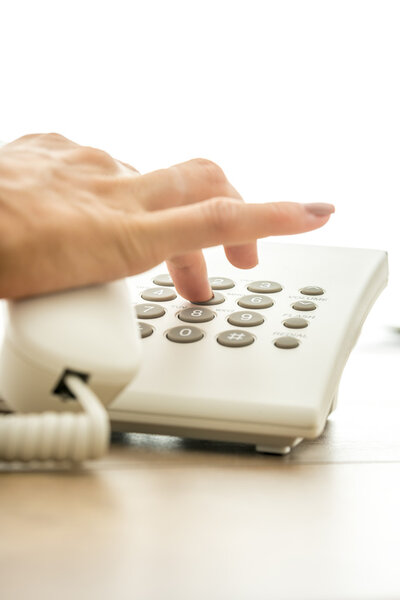 Closeup of female hand dialing a telephone number to make  a per