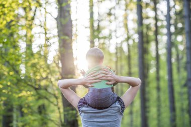 View from behind of a young mother walking with her baby son in
