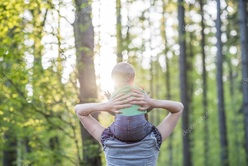 View from behind of a young mother walking with her baby son in