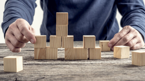 Man in blue shirt arranging wooden blocks on rustic table