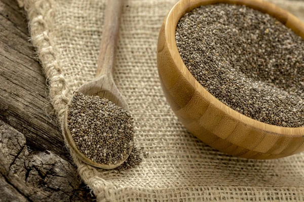 Wooden spoon and bowl full of healthy nutritious chia seeds — Φωτογραφία Αρχείου