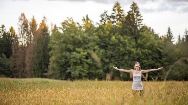 Mladá žena stojící uprostřed podzimní louka s vysokým go — Stock fotografie