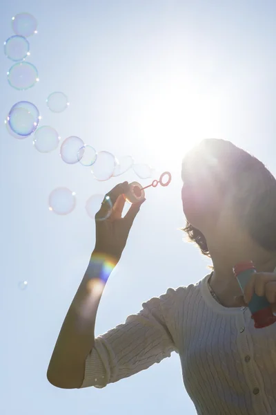 Young woman blowing soap bubbles — Stock Photo, Image