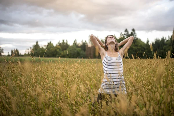 Wanita muda berdiri di tengah padang rumput musim gugur dengan tinggi pergi — Stok Foto