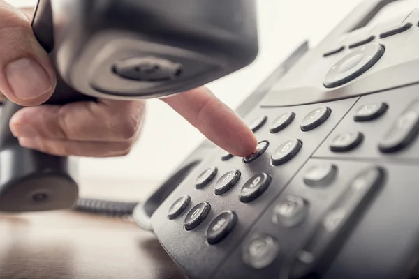 Closeup of male hand holding telephone receiver while dialing a — Stock Photo, Image