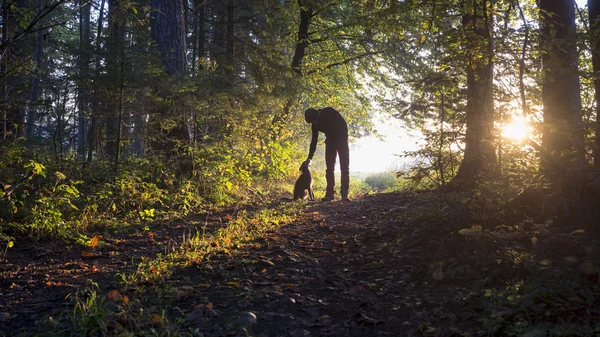 Homme se penchant pour caresser son chien noir comme ils jouissent d'une belle — Photo