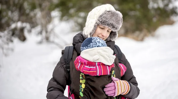 Happy young mother carrying her baby in a carrier — Stock Photo, Image