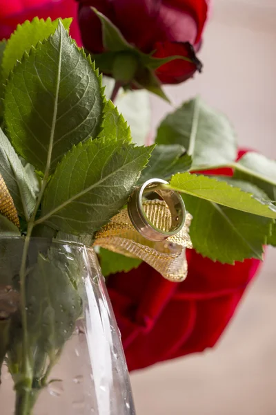 Zbliżenie pierścionek zaręczynowy wiszące z liści czerwonej kwitnący r — Zdjęcie stockowe