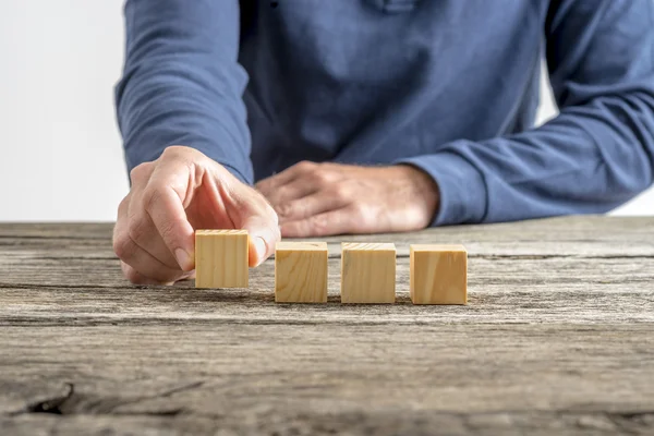 Male hand placing four blank wooden cubes in a row — Φωτογραφία Αρχείου