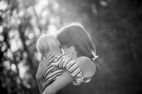 Schwarz-Weiß-Bild einer glücklich lächelnden jungen Mutter, die ihn umarmt — Stockfoto