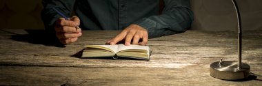 Man sitting at his work desk about to make a note in his notepad