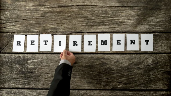 Male hand assembling the word Retirement — Stock Photo, Image