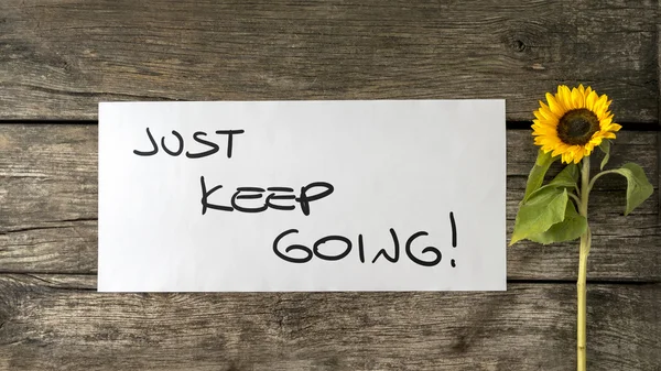 Just keep going message written on white card lying next to a bl — Stock Photo, Image