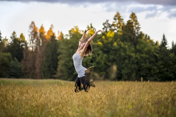Feliz alegre jovem mulher pulando no ar no meio de g — Fotografia de Stock