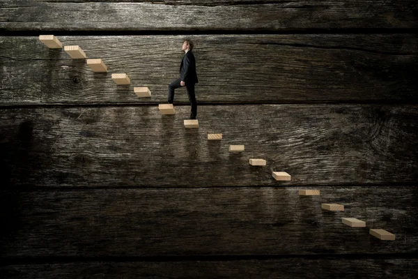 Businessman walking up on wooden stairway — Stock Photo, Image