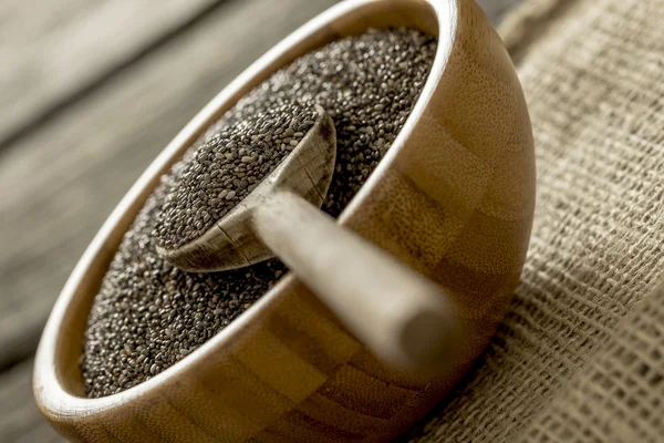 Wooden bowl full of healthy dried chia seeds with wooden spoon i — Stock Photo, Image