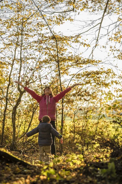 Happy young mother and her toddler son throwing autumn leaves hi — Stock Photo, Image