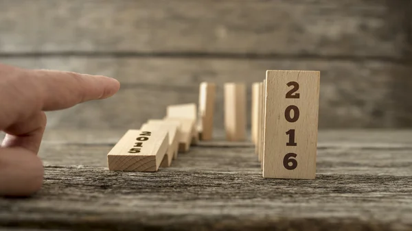 Male hand knocking down a line of domino with the first one hold — Stock Photo, Image