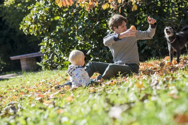 Joven padre y su hijo pequeño sentado en una hierba de otoño pl Imagen De Stock