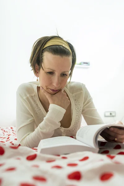 Junge Frau auf einer gepunkteten Tagesdecke liegend, auf ihren Arm gestützt wh — Stockfoto