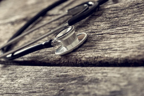 Stethoscope with black tubes lying on textured wooden boards — Stock Photo, Image