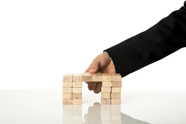 Hand of a businessman assembling a bridge of wooden pegs — Stock Photo, Image