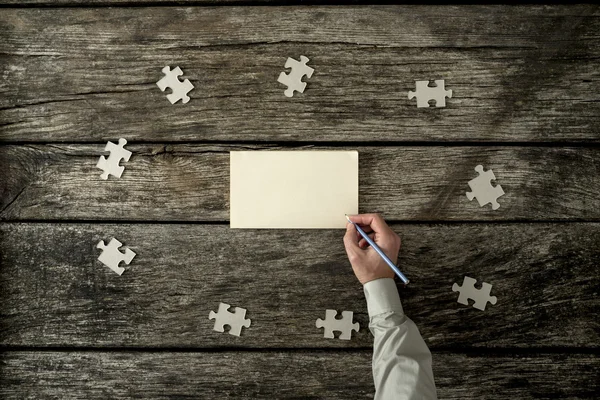 Bovenaanzicht van mannenhand schrijven op een blanco papier liggend op een textur — Stockfoto