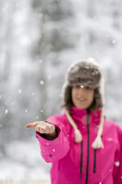 Young woman standing in a snow extending her arm in front of her — Stock Photo, Image