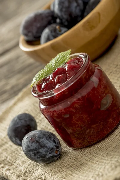 Cadre avec un bocal en verre de confiture de prunes sur un sac en toile de jute avec — Photo