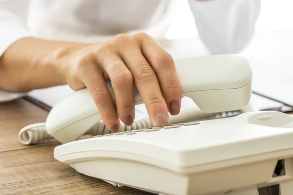 Weibliche Hand mit weißem Festnetztelefon und Wählscheibe — Stockfoto