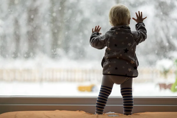 Niño pequeño de pie frente a una gran ventana apoyada contra — Foto de Stock