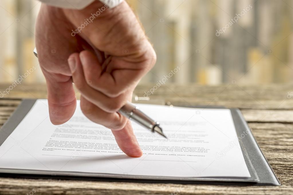 Male hand holding a pen pointing to a line at the end of a contr