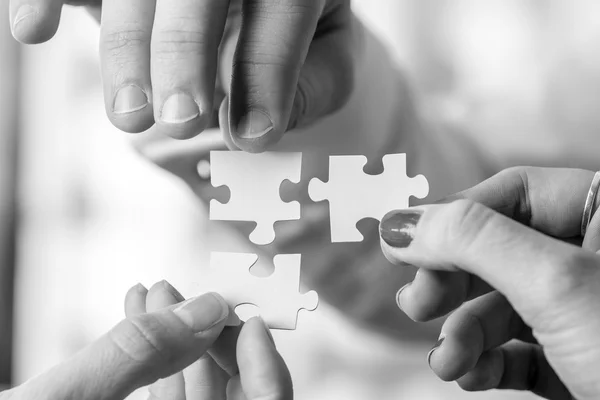 Black and white image of three people holding puzzle pieces to m — Stock Photo, Image